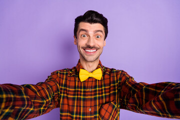 Photo of cheerful guy take selfie toothy white smile wear bow tie checkered shirt isolated violet background
