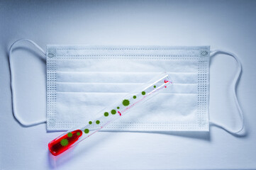 Medical mask on a white background on which there is a test tube with blood infected with the...