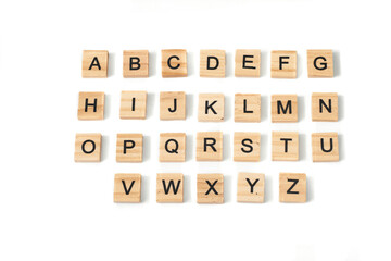Top view of english alphabet made of square wooden tiles with the English alphabet scattered on a white background with space for text. The concept of thinking development, grammar.