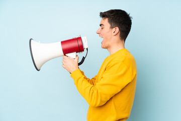 Teenager caucasian handsome man isolated on purple background shouting through a megaphone