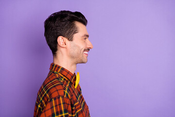 Profile photo of cheerful positive guy look empty space shiny smile wear bow tie plaid shirt isolated violet background