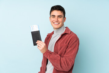 Teenager caucasian man isolated on purple background happy in vacation with passport and plane tickets