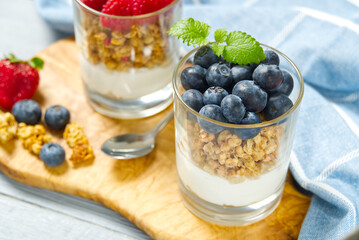 Yogurt with granola and fresh blueberries and raspberry, in glass. Healthy breakfast: yogurt parfait with granola and berries