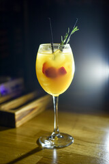 wine glass with yellow drink with fruit in it on dark background