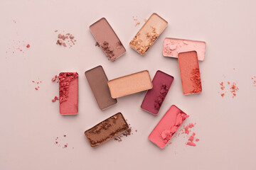 A broken eye shadow make up palette on a beige background. Beauty and cosmetic concept.