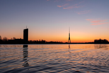 Naklejka premium The tallest tower in the European Union - Radio and TV tower in Riga, Latvia during colorful sunrise over the Daugava river