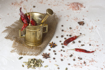 Copper mortar with chilly pepper and spices on a white table