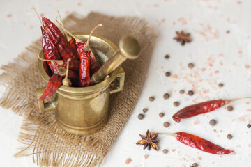 Copper mortar with chilly pepper and spices on a white table