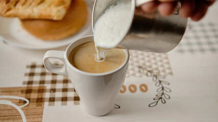 Dolewanie spienionego mleka do kubka z kawą