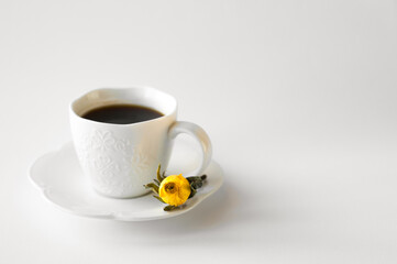 A cup of hot fresh black coffee with foam on a white background. Coffee cup on a round saucer centered inside the frame. Top view with place for text. Morning, energy and vigor concept.