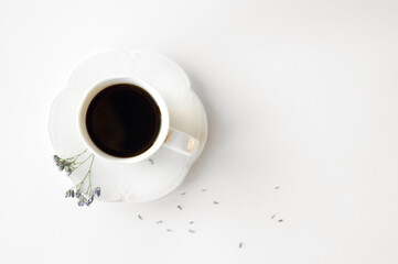 A cup of hot fresh black coffee with foam on a white background. Coffee cup on a round saucer centered inside the frame. Top view with place for text. Morning, energy and vigor concept.