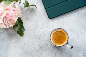 A cup of coffee, tablet and flowers on the table. Copy space. Top view.