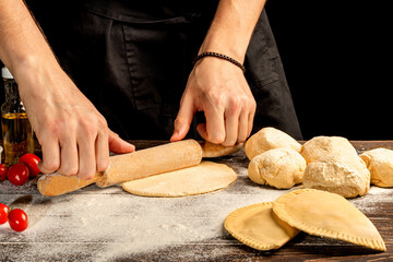 The cook prepares pasties. Step-by-step instruction. Forms the dough. Wooden background.