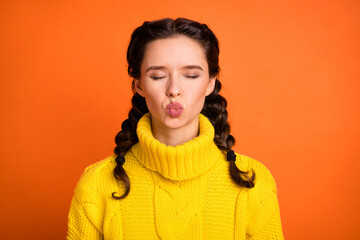 Portrait of brown hair optimistic girl blow kiss wear yellow sweater isolated on orange color background