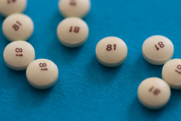 scattered low dose 81 milligrams aspirin on a turquoise blue background with a low depth of field,...
