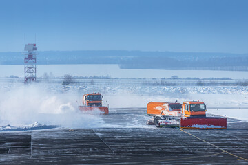 Snowplow trucks clear snowdrifts after a heavy storm blizzard at winter airport. The concept of...