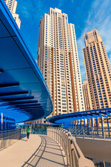 Fototapeta na wymiar The tallest residential block in the world - Jumeirah Beach Residence and original architecture pedestrian bridge in Dubai. Residential real estate and development