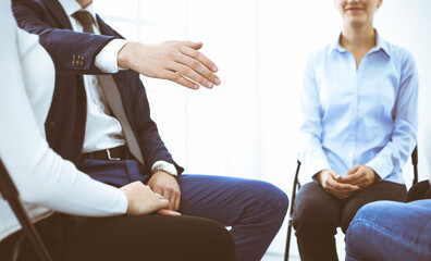 Fototapeta premium Group of people sitting in a circle during therapy in office. Meeting of business team participating in training