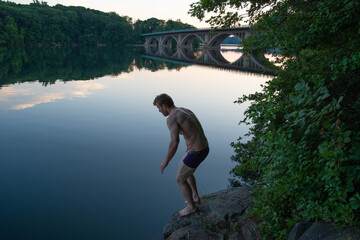 Young fit man right before jumping in to the lake