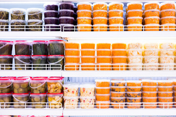 pickled vegetables, carrots, cabbage, cucumbers in plastic jars onmarket counter