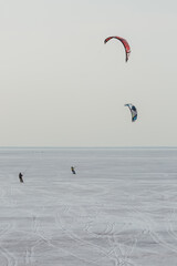 Two kite sailors sliding on the ice of the sea shore.