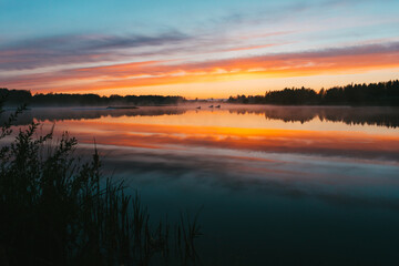 Colorful sunset over the Lielais Ansis lake in Latvia. Sunset reflections in the water over the wakeboard park