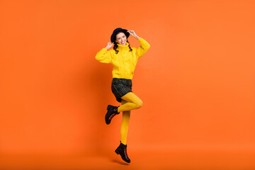 Fototapeta na wymiar Full length body size view of lovely cheerful girl jumping wearing casual enjoying isolated over bright orange color background