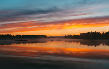 Fototapeta na wymiar Colorful sunset over the Lielais Ansis lake in Latvia. Sunset reflections in the water over the wakeboard park