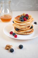 Freshly cooked delicious pancakes with honey, walnut, raspberries and blueberries for breakfast.