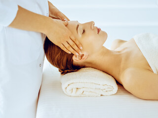 Beautiful woman enjoying facial massage with closed eyes in spa center. Relax treatment concept in medicine