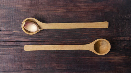 Two wooden spoons with garlic. Composition on a wooden cutting board. View from above.