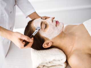 Beautiful brunette woman enjoying applying cosmetic mask comfortable and bissfulle. Relaxing treatment in medicine and spa center concepts