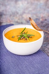 Homemade pumpkin soup puree with rosemary and a blue cotton napkin