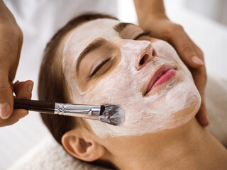Beautiful brunette woman enjoying applying cosmetic mask comfortable and bissfulle. Relaxing treatment in medicine and spa center concepts