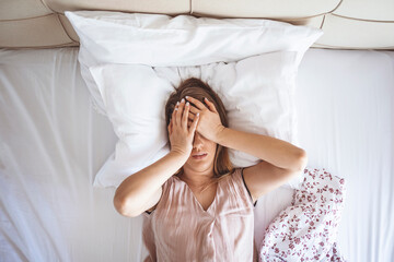 Young beautiful Caucasian woman on bed having headache / insomnia / migraine / stress. Young woman...