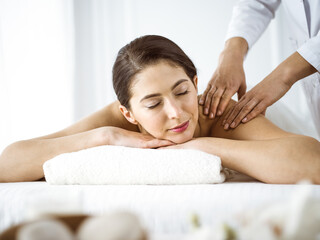 Obraz na płótnie Canvas Beautiful brunette woman enjoying back massage comfortable and blissful. Spa and medicine concept
