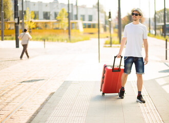 Full length excited traveler tourist man sit on train station platform taxi. Passenger travel on weekend. Air flight journey concept