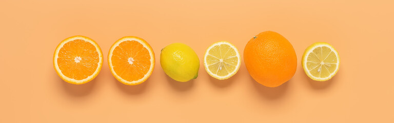 Fresh oranges and lemons in a line on a pastel peach background. Border. View from above.