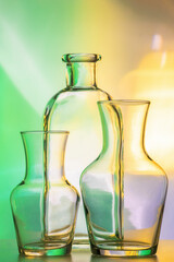 three items - transparent vases and a bottle. Still life abstract, on a colored yellow-green background. For design and decoration
