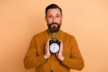 Photo of disappointed mature man late hold clock isolated over beige color background