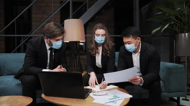 A team of multinational businessmen in suits and medical masks decide to cooperate internationally on investment in the development of IT technologies during the Covid19 pandemic in the meeting room.