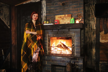 beautiful girl with a plaid near the fireplace