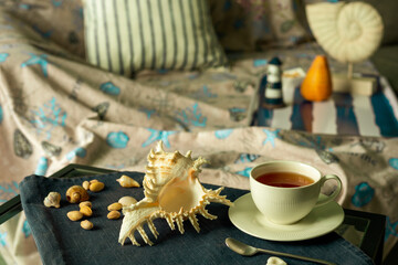 Marine style in the interior - a sofa and a table with a cup of tea and a seashell