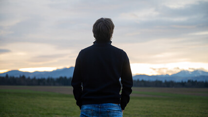 young man standing under a beautiful evening sky relaxing, enjoying and meditating