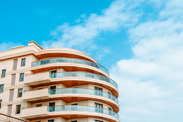 A multi-storey residential or business modern building with a rounded shape against the blue sky