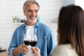 Happy Couple Enjoying Wine While Working In Kitchen.