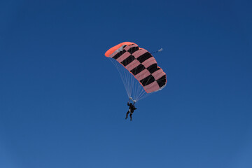 Skydiving. A parachute is in the blue sky.