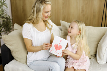 Happy mother day. Child daughter congratulates mom and gives her postcard with heart drawing. Family and childhood concepts