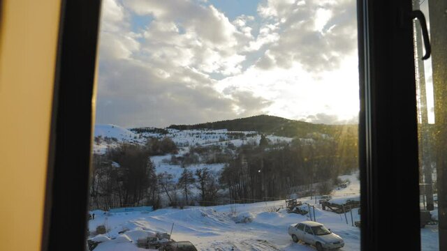 Snow landscape view through the window. View from the window to the snow-covered mountain. Beautiful winter landscape. Trees in the snow. Frosty winter morning.