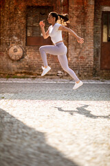 Fototapeta na wymiar Young woman juping high during training in the urban environment